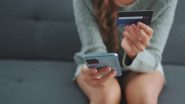 Close up of woman hands holding credit card and smartphone. Young woman paying online using banking entering data shopping order in internet store secure payment.