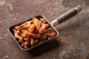 tasty fried pork fillet in an old skillet pan on rusty texture background