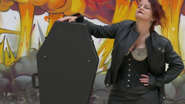 Rocker Girl Standing next to her Coffin guitar case. Medium shot slow motion.