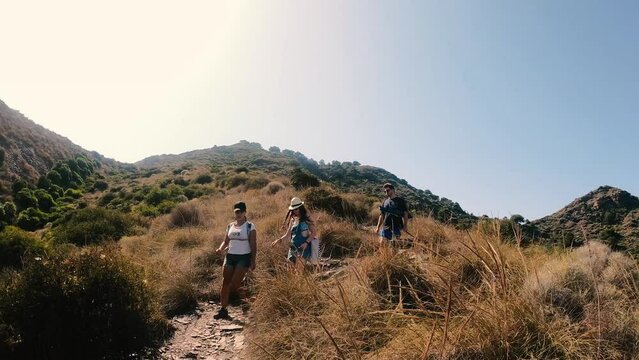 Hikers walking in group at mountain forests and pathways. Group of people hiking in hill landscape.