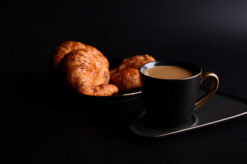 Hot latte coffee with Croissant coffee break isolated in black background