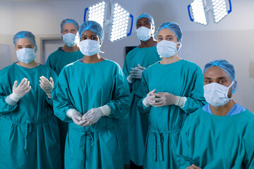 Portrait of diverse surgeons wearing surgical gowns in operating theatre at hospital