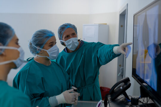 Diverse surgeons looking at x-ray scans in operating theatre at hospital