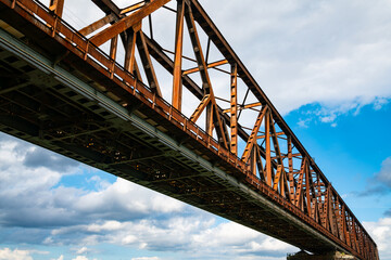 Historic railway bridge over river Rhine in Duisburg, Germany. Steel rivet construction with diagonal truss beams is in bad condition with rusty surface. Main railroad from Ruhr basin to Aachen.