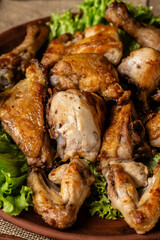 Georgian cuisine. Fried chicken legs and wings with Georgian spices and greens on a plate. Restaurant food.