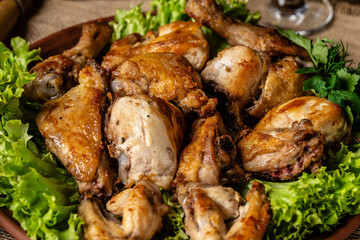Georgian cuisine. Fried chicken legs and wings with Georgian spices and greens on a plate. Restaurant food.