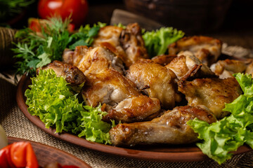 Georgian cuisine. Fried chicken legs and wings with Georgian spices and greens on a plate. Restaurant food.
