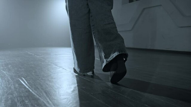 Young woman entering stage with smoke on background. Close-up of woman legs entering stage. Elegant female heels dancer. Silhouette of dancer legs walking through dark studio. Tracking shot in 4K, UHD