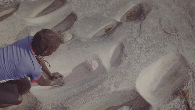 Lotuko tribe woman grinding grains in a hole in the rock Illeu South Sudan