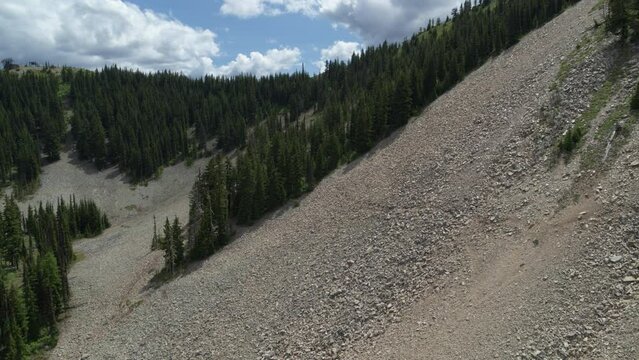Aerial above steep talus field on side of mountain in forest in northern Idaho in summer
