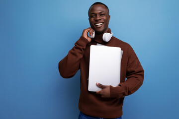 successful young american student with laptop and headphones on background with copy space