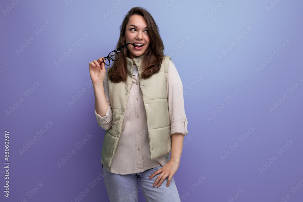 Sticker young brunette woman holding glasses in her hands on a studio background with copy space