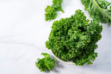 Kale in bowl on marble background. curly kale. - obrazy, fototapety, plakaty