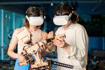 Young man and woman in VR glasses doing experiments in robotics in a laboratory