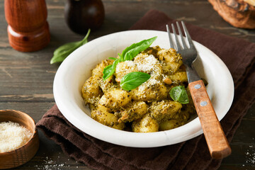 Potato gnocchi. Traditional homemade potato gnocchi with sauce pesto, kitchen table and basil on old dark rustic turquoise kitchen table. Traditional Italian food. Top view.