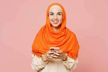Young arabian asian muslim woman wear orange abaya hijab hold in hand use mobile cell phone...