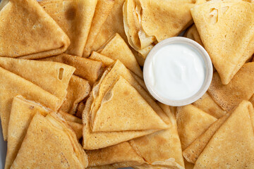 Heap of crepes or thin pancakes with sour cream. Food background. Top view.