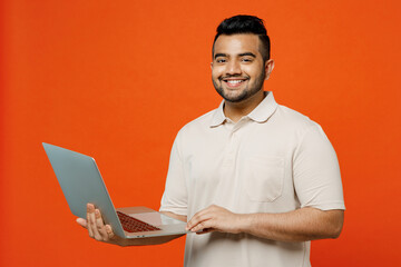 Young fun smiling smart IT Indian man he wears white t-shirt casual clothes hold use work on laptop...