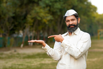Indian or marathi man in traditional wear. showing copyspace pointing.