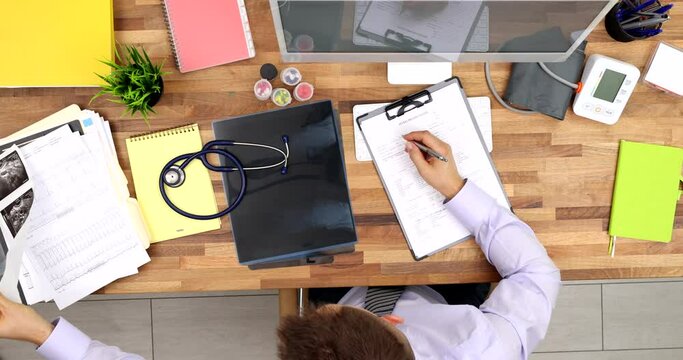 General practitioners fill paper medical records top view. Physician generalist cardiologist makes paperwork at workplace writes notes prepares documents reports or prescription