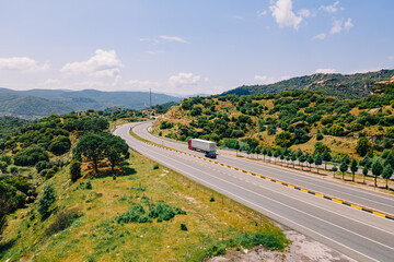 Truck speeds along the highway running across mountains, aerial shot