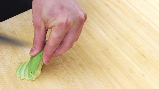 Chef Slicing Avocado On A Wooding Chopping Board Indoors