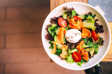 salad with fresh vegetables and fish pieces on the cafe table. light salad with avocado and salmon slices in a summer restaurant