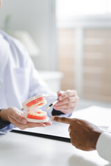 Dentist explaining endodontic treatment to patient in office Dentist holding a tooth model for examination and research