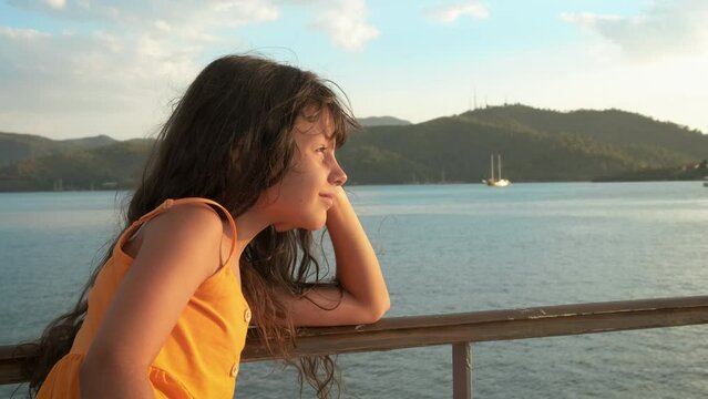 Child relaxation time on ship deck. A hopefull little girl relax on sea terrace under evening sun during summer time.
