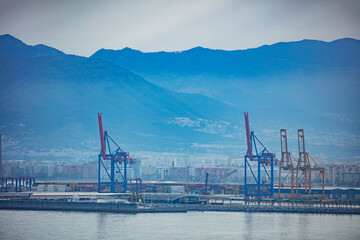 Industrial cargo terminal with port cranes and Malaga cityscape