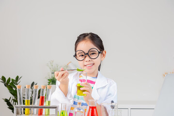 Asian little girl working with test tube science experiment in white classroom