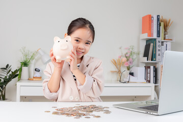 Asian little cute girl wearing a cream suit analyzing coins finance and investment