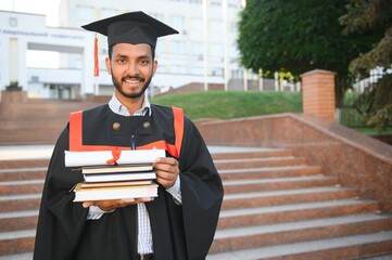 Portrait of indian handsome male graduate in graduation robe.