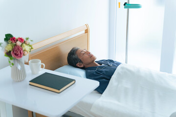 酸素チューブをつけてベッドに寝るシニア男性