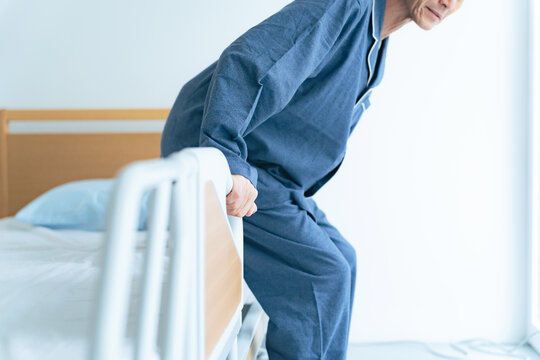 介護ベッドから立ち上がるシニア男性