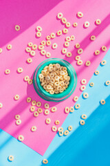 Cereals corn flakes or rings in a bowl and around it on pink and blue background, flat lay, top view. - 630642590