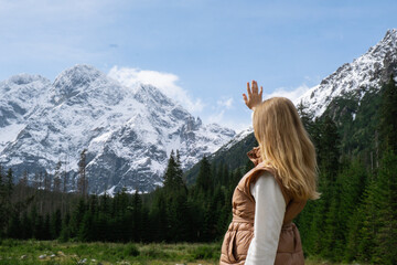 Young woman enjoying nature in Morskie Oko Snowy Mountain Hut in Polish Tatry mountains Zakopane Poland. Naturecore aesthetic beautiful green hills. Mental and physical wellbeing Travel outdoors