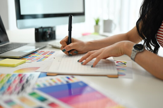Young creative woman working with color palette, choosing color samples for design project at graphic studio.