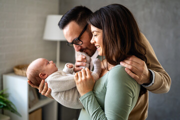 Proud mother and father smiling at their newborn baby daughter, son at home