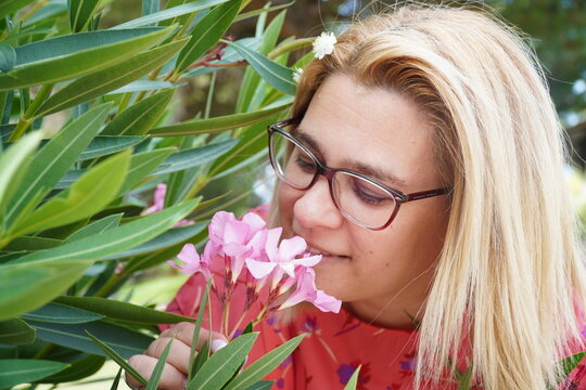 Lady smeling a pink flower on the park.