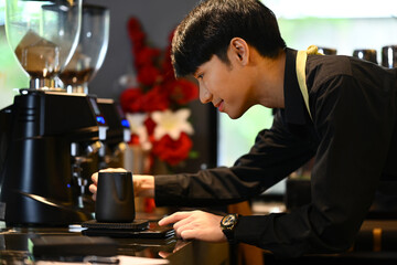 Smiling male barista preparing coffee for customer order in trendy coffee. Small business concept.