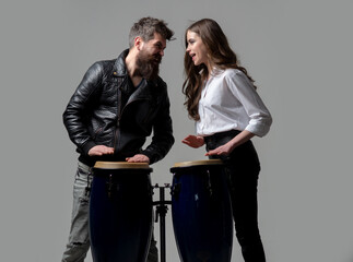 Man and woman playing conga drums. Couple hitting on conga drums isolated on gray background