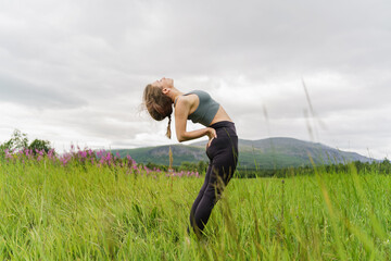 Mental health and meditation. Yoga training in nature, a woman doing asana. Trainer exercises fitness clothing. Motivation is a healthy lifestyle for a person.