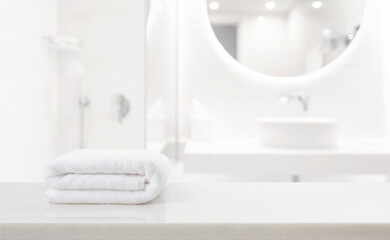 Fresh white spa towel on countertop in blurred moderm bathroom