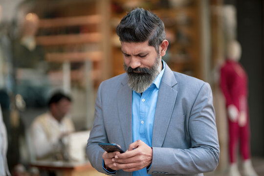 Indian businessman giving stressful expression after looking in smartphone