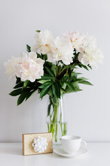 Beautiful white peonies bouquet in vase, gift and cup of coffee