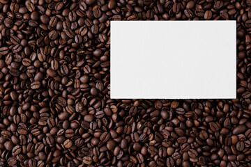 Top view of blank paper card with copyspace on background from coffee beans