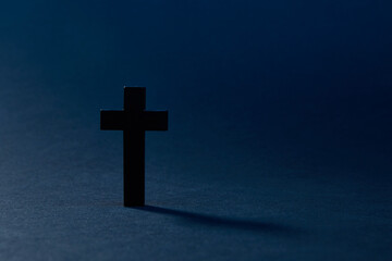 Black cross isolated on the dark solid fond blue background
