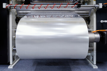 roll of plastic packaging film on the automatic packing machine in food product factory. industrial...