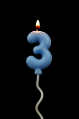 Burning air balloon shaped birthday candle isolated on black background, number 3.